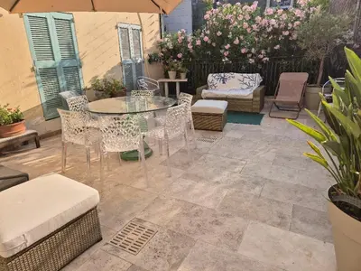a patio with a glass table and chairs and flowers at Terrasse Bergerie in Cannes