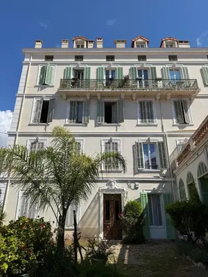 a large white building with balconies and a tree at Studio Cannes, near Croisette in Cannes