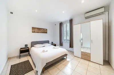 a white bedroom with a bed and a sliding glass door at 2 Pièces vieille-ville Cannes - Suquet - Proche Palais et Croisette in Cannes
