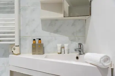 a white bathroom with a sink and a mirror at 2 Pièces vieille-ville Cannes - Suquet - Proche Palais et Croisette in Cannes