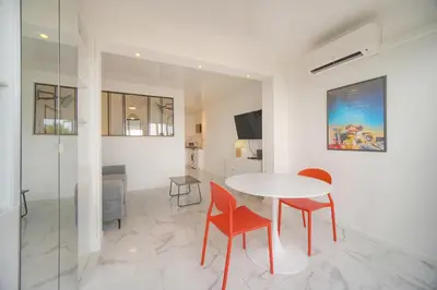 a living room with a table and chairs and a television at Le Cali - Front de mer - Palm Beach - VCA in Cannes