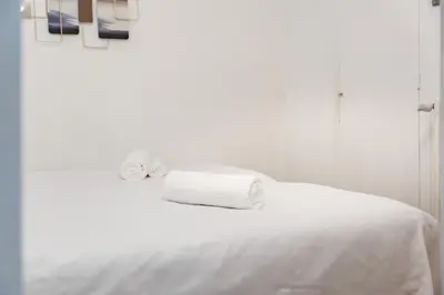 a white bed with two rolls of towels on it at 3 pièces centre-ville Cannes - Croisette - Climatisation séjour in Cannes