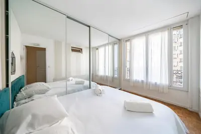 a large white bedroom with two beds and a mirror at 3 pièces centre-ville Cannes - Croisette - Climatisation séjour in Cannes