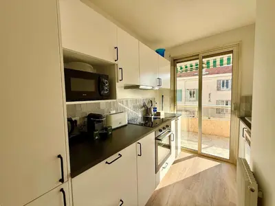 a kitchen with white cabinets and a black counter top at C018 - Lumineux Appartement - Proche plage in Cannes