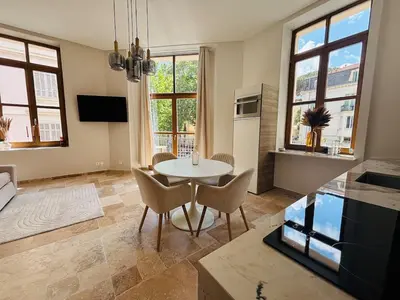 a living room with a table and chairs and windows at Le Sainte Rose Standing, Cannes center on foot in Cannes