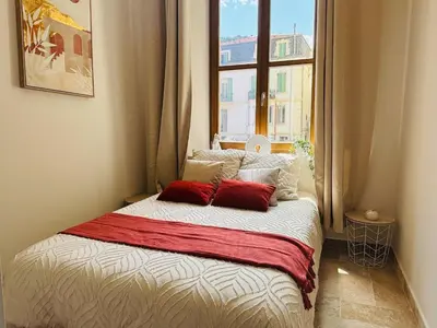 a bed with two red pillows in a room with a window at Le Sainte Rose Standing, Cannes center on foot in Cannes