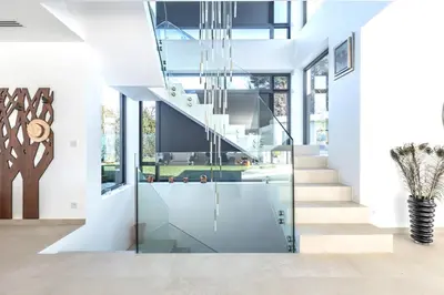 a glass pivot door in a house with a staircase at Villa Dream Cannes in Cannes