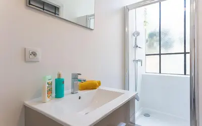 a white bathroom with a sink and a shower at Aura Apartments by Halldis in Cannes