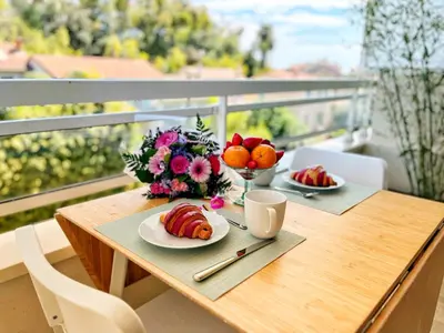 a table with a plate of food and flowers on a balcony at Cannes Breeze in Cannes