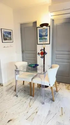 a dining room with a glass table and white chairs at Studio basse californie cannes in Cannes