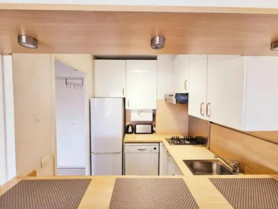 a kitchen with white cabinets and a stainless steel refrigerator at T2 Vue dégagée proche Cannes in Le Cannet