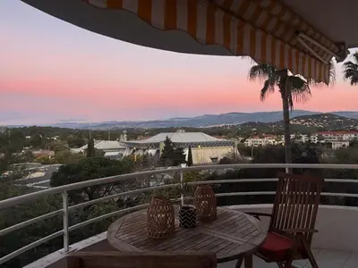 a table and chairs on a balcony with a sunset at T2 Vue dégagée proche Cannes in Le Cannet