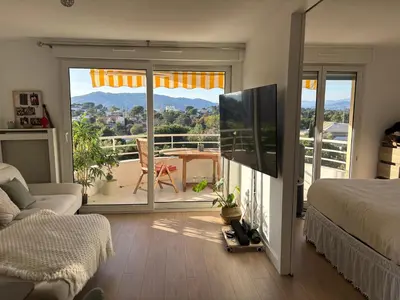 a bedroom with a bed and a balcony with a view at T2 Vue dégagée proche Cannes in Le Cannet