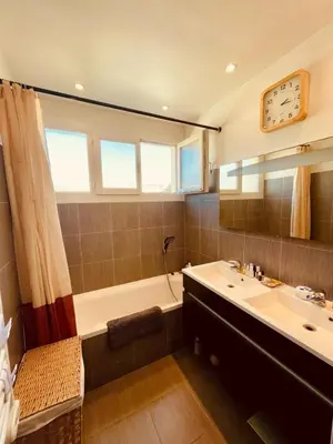 a bathroom with a tub and a sink and a clock at Bel Appartement lumineux avec balcon in Le Cannet