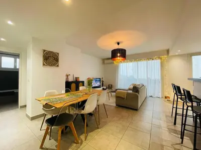 a kitchen with white cabinets and a bar with stools at Bel Appartement lumineux avec balcon in Le Cannet