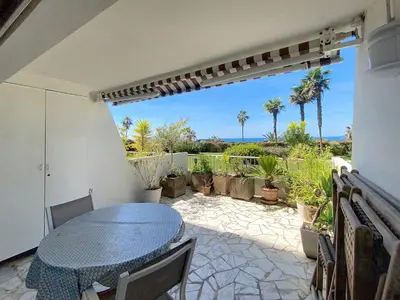 a patio with a table and chairs and palm trees at Superbes prestations grande terrasse 352L in Cannes