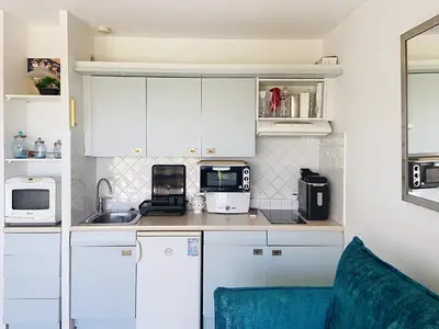 a kitchen with white cabinets and a blue chair at Superbes prestations grande terrasse 352L in Cannes