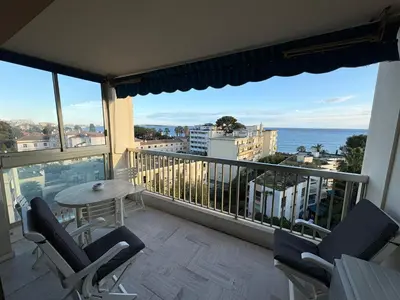 a balcony with chairs and a table and a view of the ocean at Appartement vue & front de mer, piscines, 55M2 2Pièces in Cannes
