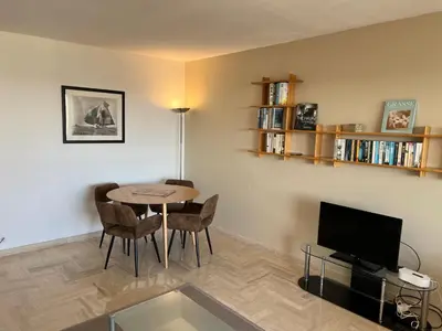 a living room with a table and chairs and a tv at Appartement vue & front de mer, piscines, 55M2 2Pièces in Cannes