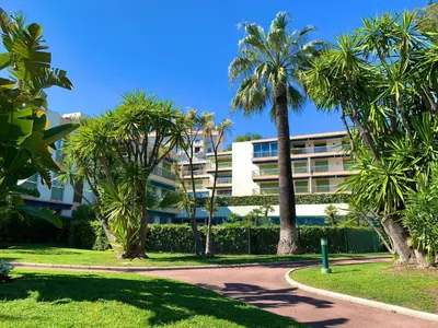 a building with palm trees in a park at Appartement vue & front de mer, piscines, 55M2 2Pièces in Cannes