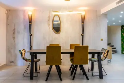 a dining room with two tables and yellow chairs at Appartement en bord de mer avec piscine - Cannes in Cannes