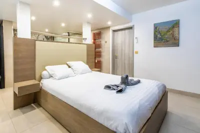 a bedroom with a large bed with white sheets at Appartement en bord de mer avec piscine - Cannes in Cannes