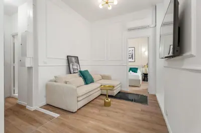 a white living room with a couch and a tv at Appartement Montrose - Welkeys in Cannes