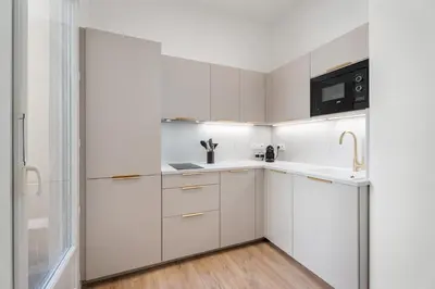 a white kitchen with a sink and a microwave at Appartement Montrose - Welkeys in Cannes