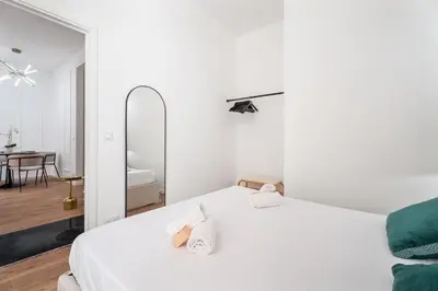 a white bedroom with a bed and a mirror at Appartement Montrose - Welkeys in Cannes