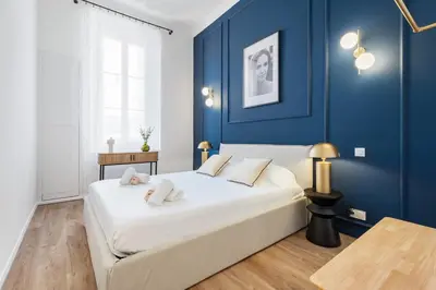 a bedroom with a large bed with blue walls at Appartement Prado - Welkeys in Cannes