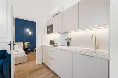 a kitchen with white cabinets and a sink at Appartement Prado - Welkeys in Cannes