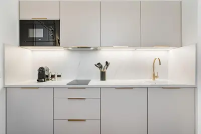 a white kitchen with white cabinets and a sink at Appartement Prado - Welkeys in Cannes