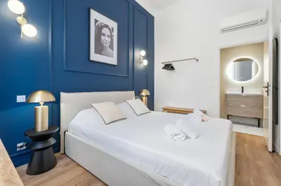 a bedroom with a white bed and blue walls at Appartement Prado - Welkeys in Cannes