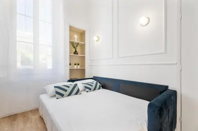 a white bedroom with a bed and a cabinet at Appartement Prado - Welkeys in Cannes