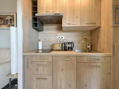 a small kitchen with wooden cabinets and a sink at Le Beauséjour, studio with pool, parking, air conditioning in Le Cannet