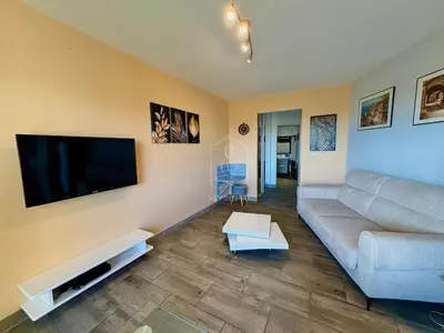 a living room with a couch and a flat screen tv at Le Beauséjour, studio with pool, parking, air conditioning in Le Cannet