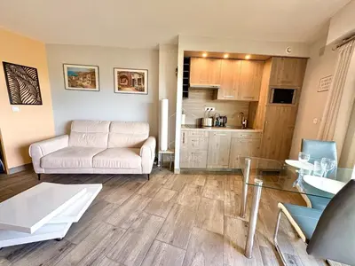 a living room with a white couch and a table at Le Beauséjour, studio with pool, parking, air conditioning in Le Cannet
