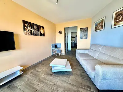 a living room with a couch and a flat screen tv at Le Beauséjour, studio with pool, parking, air conditioning in Le Cannet