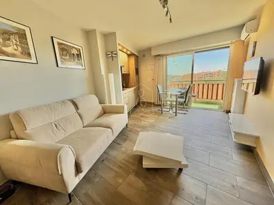 a living room with a couch and a table at Le Beauséjour, studio with pool, parking, air conditioning in Le Cannet