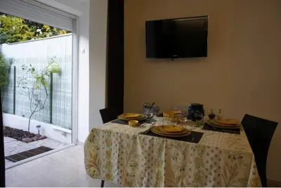 a dining room table with plates and a television on the wall at CANNES POINTE CROISETTE Garden & Beach in Cannes