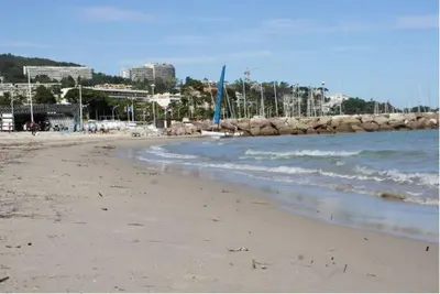 a sandy beach with the ocean and buildings in the background at CANNES POINTE CROISETTE Garden & Beach in Cannes