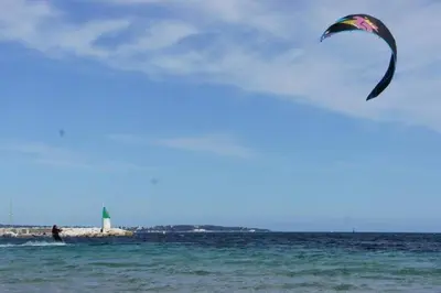 a person flying a kite on the ocean with a lighthouse at CANNES POINTE CROISETTE Garden & Beach in Cannes