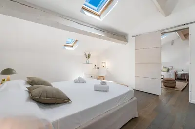 a white bedroom with a large bed with pillows at Appartement Reyer - Welkeys in Cannes