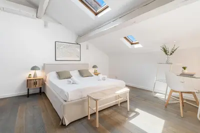 a white bedroom with a bed and a table at Appartement Reyer - Welkeys in Cannes