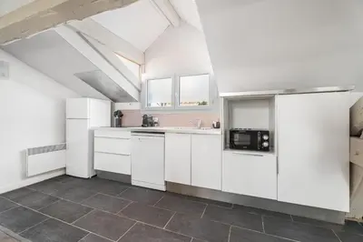 a kitchen with white cabinets and a tile floor at Appartement Reyer - Welkeys in Cannes