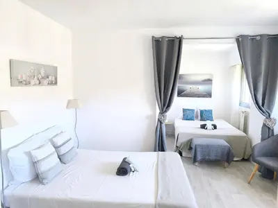 a white bedroom with two beds and a chair at Quadruple bedroom apartment in Cannes