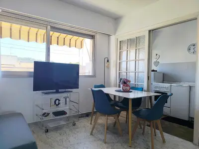 a living room with a table and chairs and a tv at Quadruple bedroom apartment in Cannes