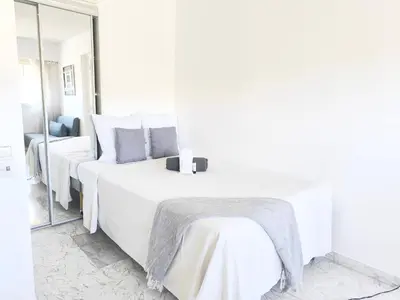 a white bedroom with two beds and a mirror at Quadruple bedroom apartment in Cannes