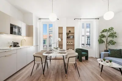a kitchen and living room with a table and chairs at Appartement Caire - Welkeys in Cannes