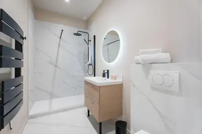 a white bathroom with a shower and a sink at Appartement Caire - Welkeys in Cannes